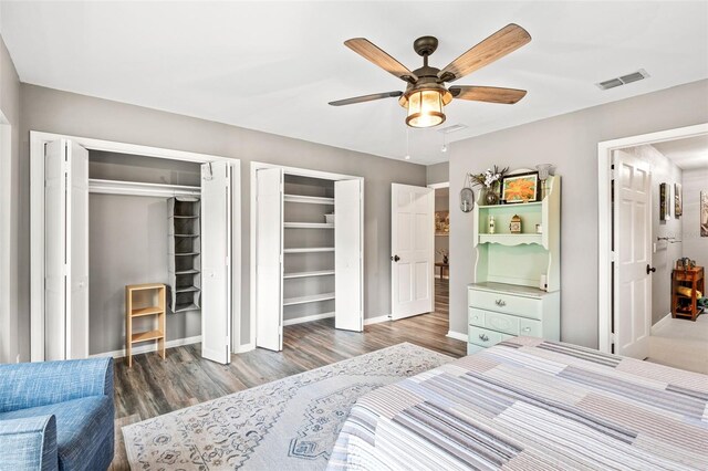 bedroom with hardwood / wood-style flooring, two closets, and ceiling fan