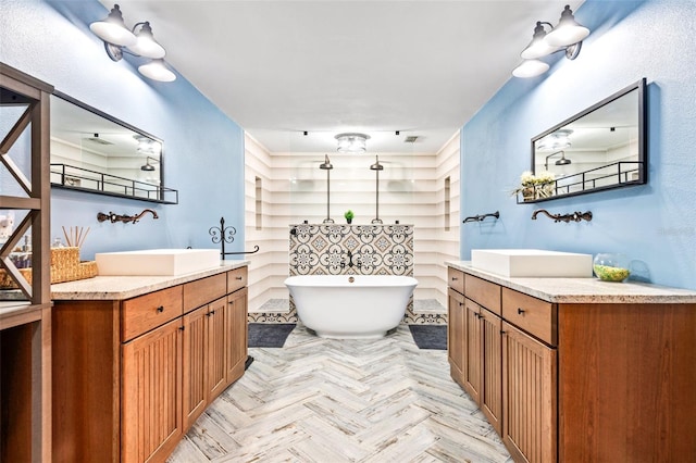 bathroom featuring a soaking tub, two vanities, a sink, and visible vents