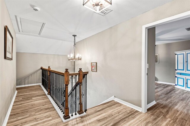 corridor featuring lofted ceiling, wood-type flooring, and a notable chandelier