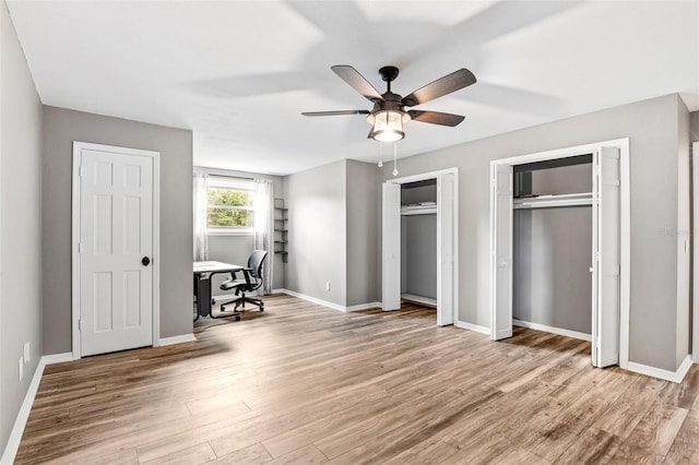 unfurnished bedroom with ceiling fan, two closets, and light hardwood / wood-style floors