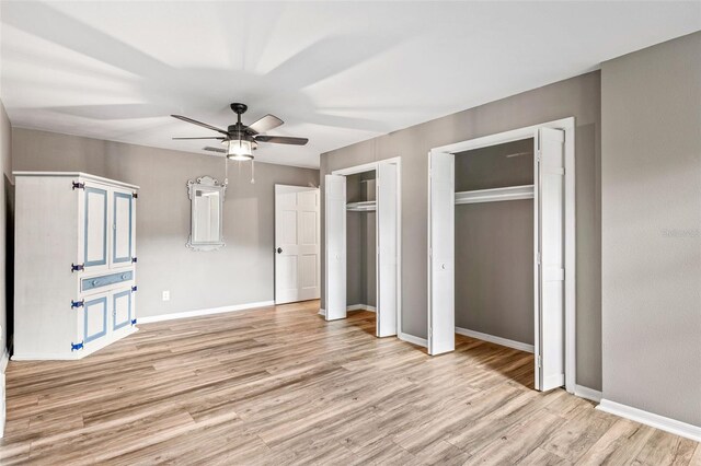 unfurnished bedroom with ceiling fan, multiple closets, and light hardwood / wood-style flooring