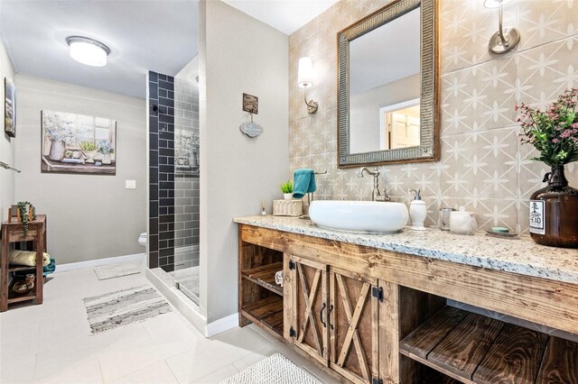 bathroom featuring tile patterned floors, toilet, a tile shower, tile walls, and vanity