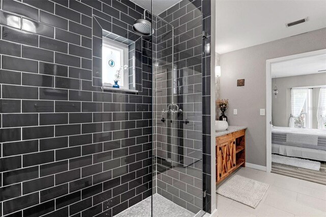 bathroom featuring vanity, a tile shower, and tile patterned flooring