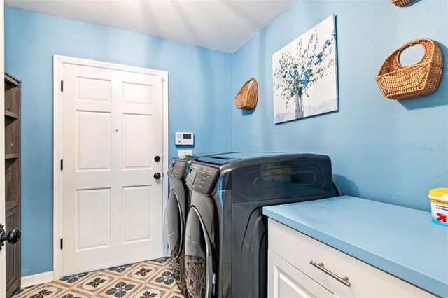 clothes washing area with cabinets and washing machine and dryer