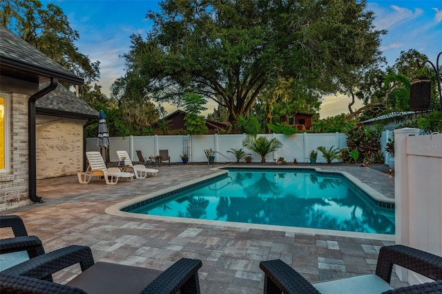 pool at dusk with a patio area