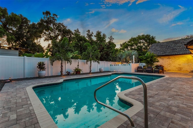 pool at dusk featuring a patio area