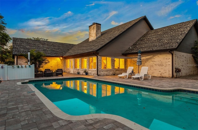 pool at dusk with a patio area