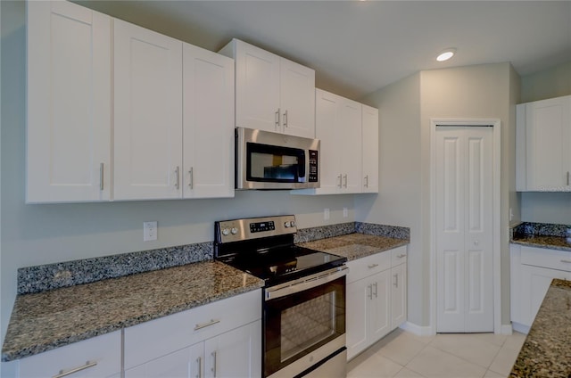 kitchen with light stone counters, light tile patterned floors, appliances with stainless steel finishes, and white cabinets