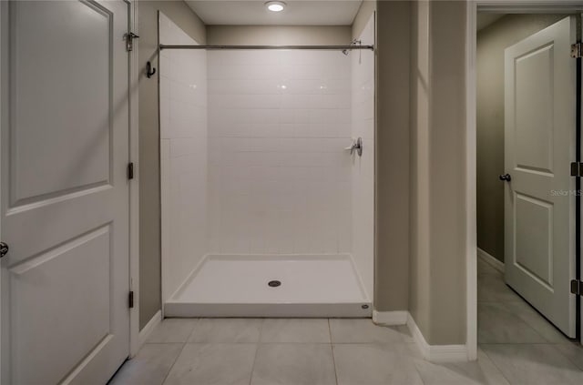 bathroom featuring tiled shower and tile patterned flooring