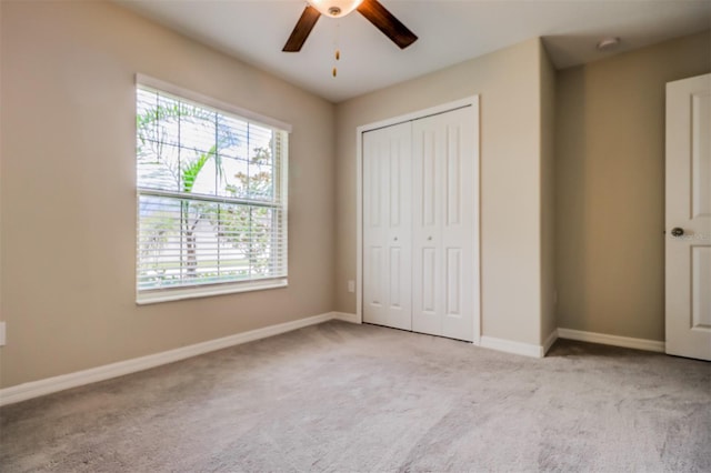 unfurnished bedroom featuring multiple windows, ceiling fan, and light carpet