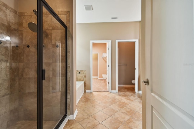 bathroom with toilet, a shower with door, and tile patterned floors