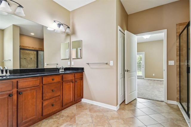 bathroom with a shower with door, vanity, and tile patterned floors