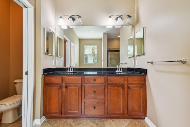 bathroom featuring a shower with door, vanity, toilet, and tile patterned floors