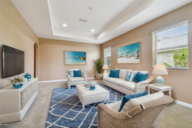 living room with a tray ceiling and carpet