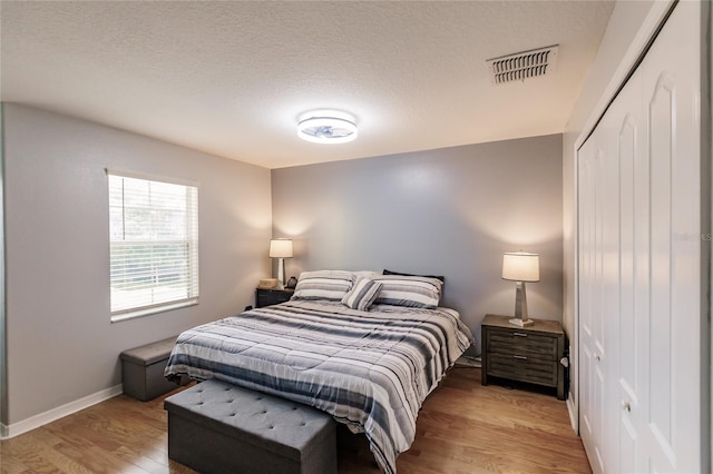 bedroom featuring light wood-type flooring, a closet, and a textured ceiling