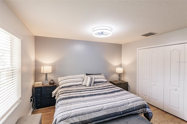 bedroom with a textured ceiling, a closet, and hardwood / wood-style flooring