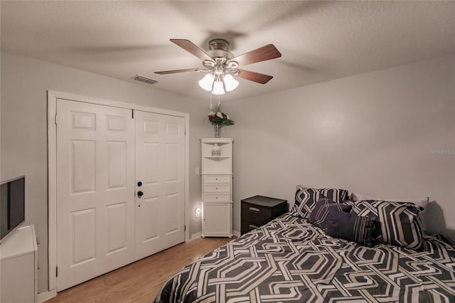 bedroom with a textured ceiling, a closet, ceiling fan, and hardwood / wood-style floors