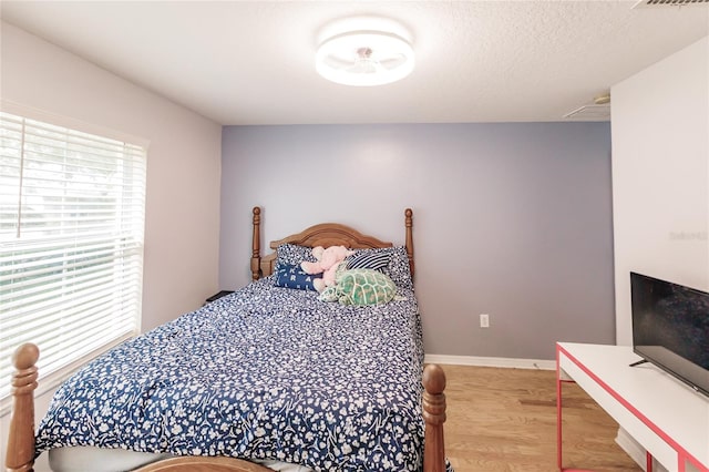 bedroom with a textured ceiling and wood-type flooring