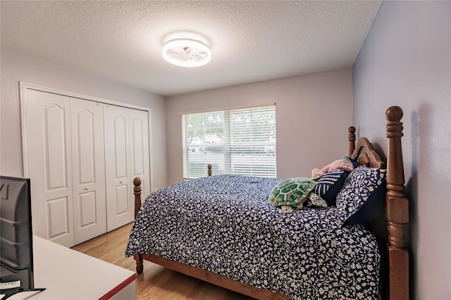 bedroom featuring a closet, a textured ceiling, and light hardwood / wood-style flooring