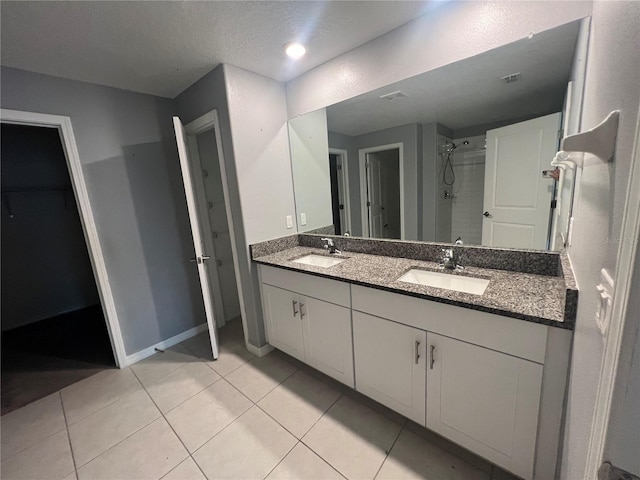 bathroom featuring vanity, a textured ceiling, tile patterned floors, and walk in shower