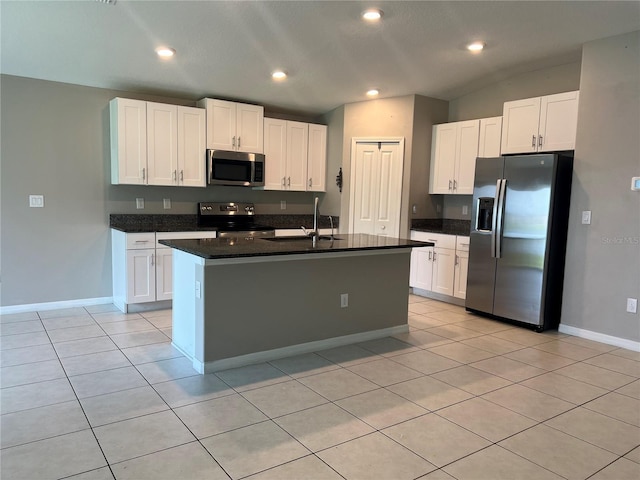 kitchen featuring light tile patterned floors, stainless steel appliances, white cabinetry, and an island with sink