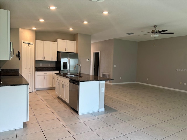 kitchen with appliances with stainless steel finishes, sink, light tile patterned floors, a center island with sink, and white cabinetry