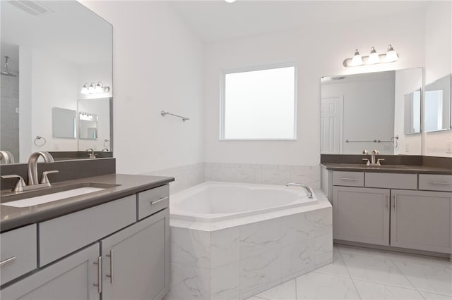 bathroom featuring tiled tub and vanity