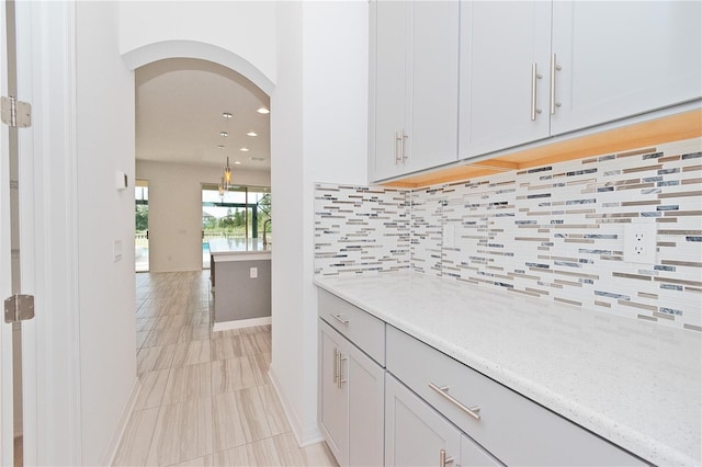 kitchen featuring light stone countertops, decorative backsplash, and light tile patterned floors