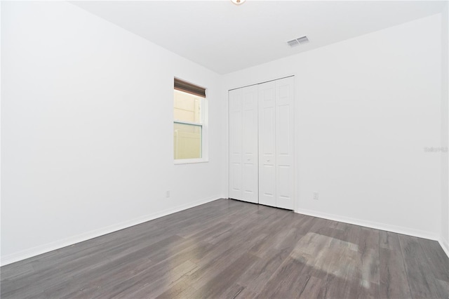 unfurnished bedroom with a closet and dark hardwood / wood-style flooring