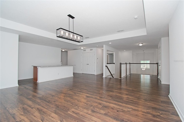 unfurnished living room with dark hardwood / wood-style floors and an inviting chandelier