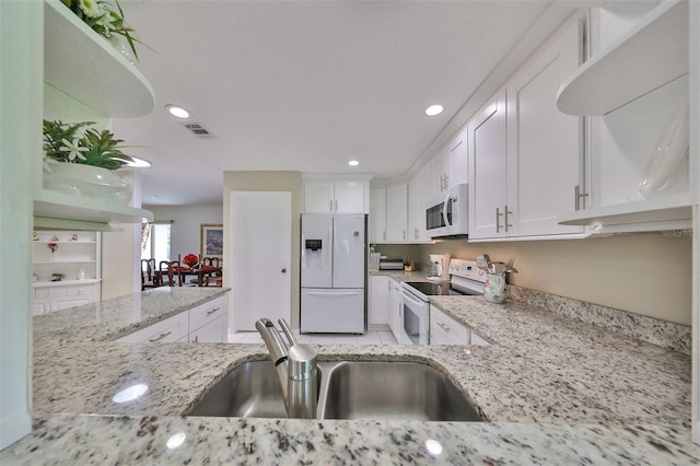 kitchen with white cabinets, white appliances, light stone countertops, and sink