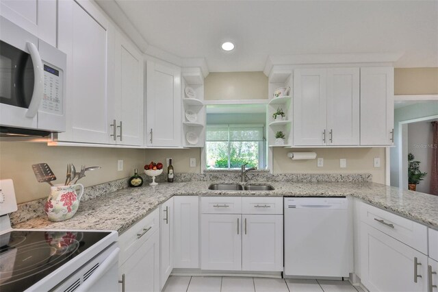 kitchen featuring light stone countertops, white appliances, light tile patterned floors, sink, and white cabinets