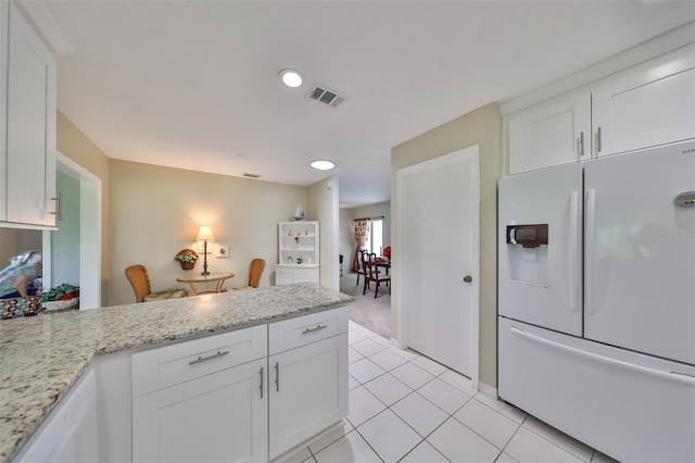 kitchen featuring white cabinetry, light stone counters, light tile patterned flooring, and white refrigerator with ice dispenser