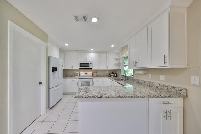 kitchen with white cabinets, white appliances, kitchen peninsula, and sink