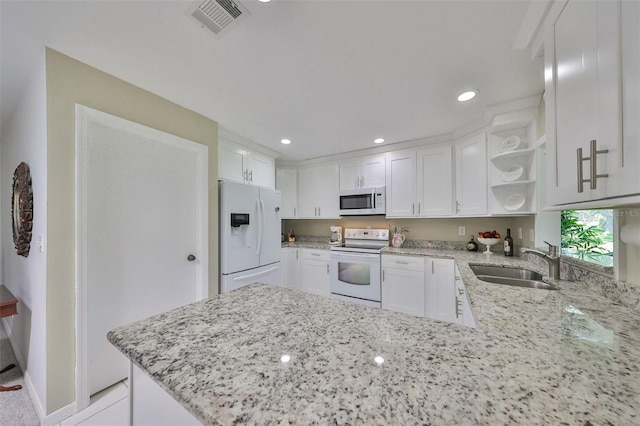 kitchen featuring white appliances, kitchen peninsula, sink, white cabinetry, and light stone counters