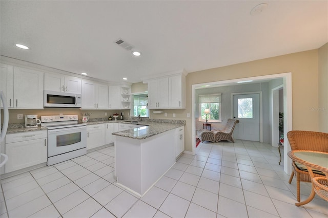 kitchen with light stone countertops, white appliances, sink, white cabinets, and light tile patterned flooring