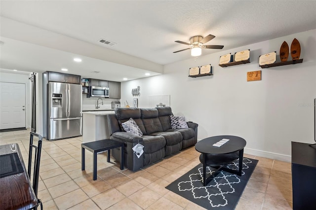 living room with ceiling fan, light tile patterned floors, and a textured ceiling