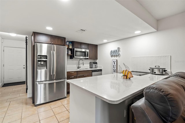 kitchen with a breakfast bar area, light tile patterned floors, appliances with stainless steel finishes, sink, and dark brown cabinetry