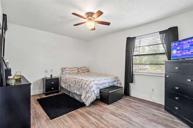 bedroom with a textured ceiling, wood-type flooring, and ceiling fan