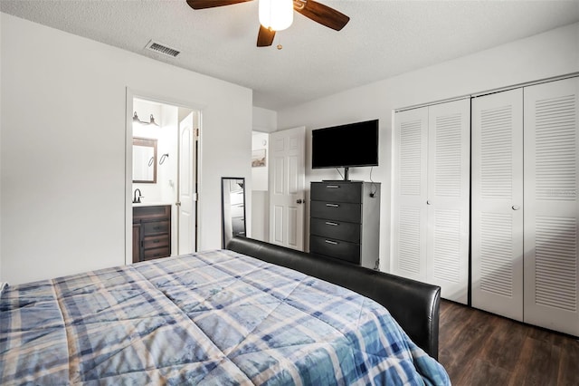 bedroom with ensuite bath, a closet, dark wood-type flooring, ceiling fan, and a textured ceiling