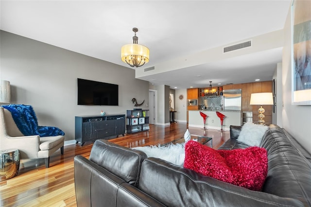 living room featuring a notable chandelier and light wood-type flooring