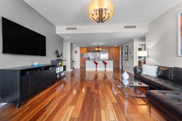 living room featuring wood-type flooring and an inviting chandelier