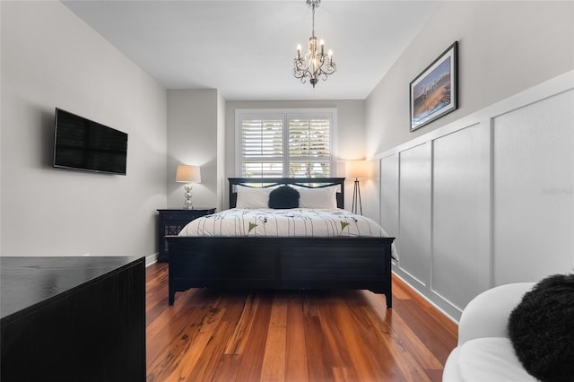 bedroom with a notable chandelier, a decorative wall, and wood finished floors