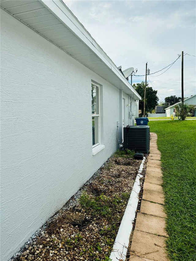 view of side of home with a yard and central air condition unit