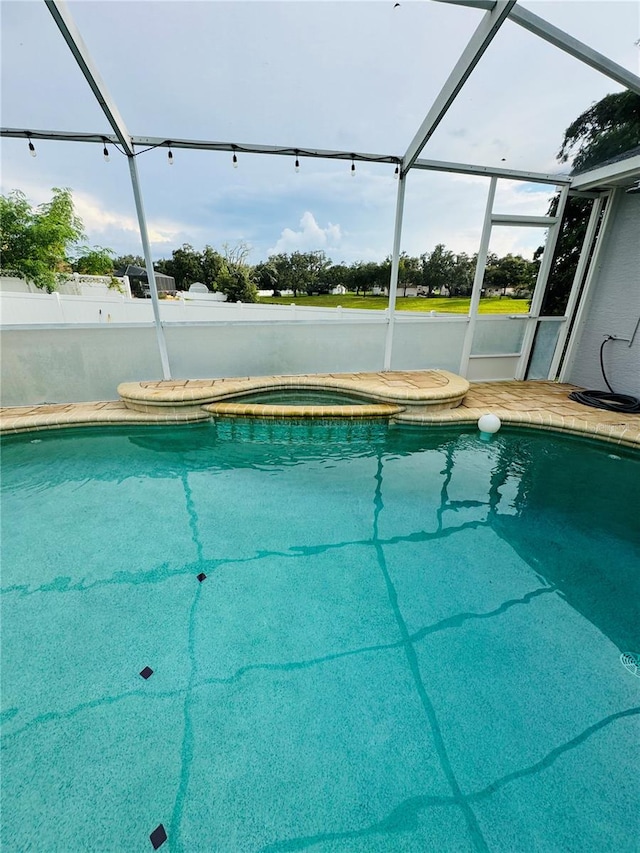 view of swimming pool featuring glass enclosure and a hot tub