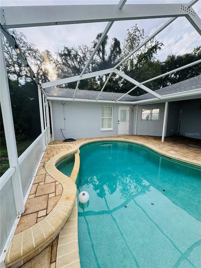 view of pool with glass enclosure and a patio