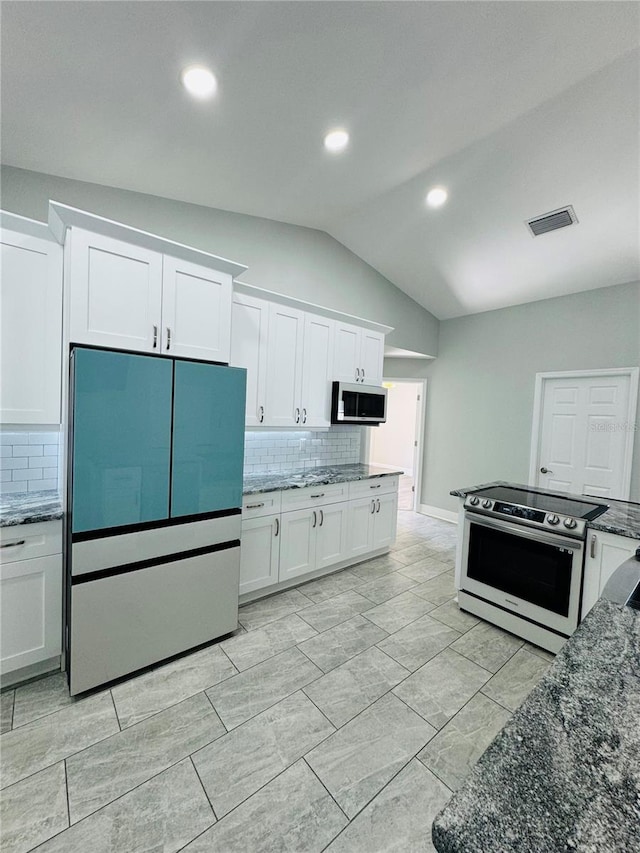 kitchen featuring dark stone countertops, appliances with stainless steel finishes, lofted ceiling, and white cabinets