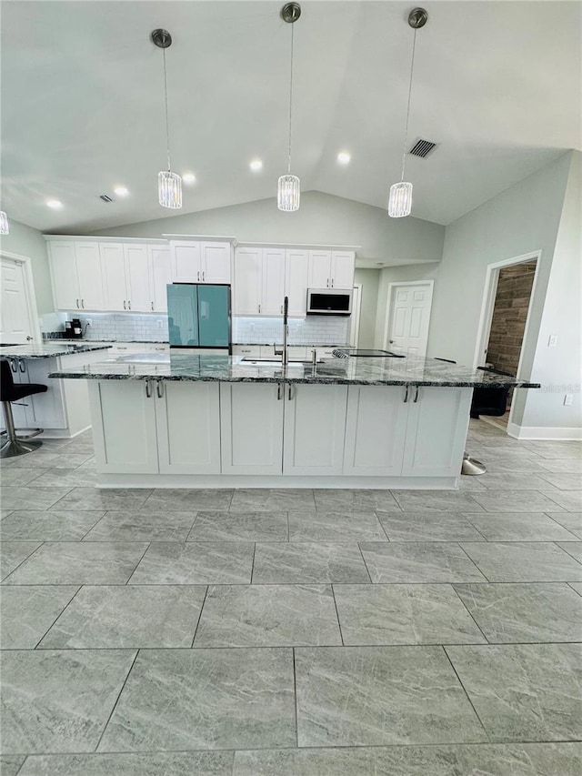 kitchen featuring a spacious island, decorative light fixtures, white cabinets, and lofted ceiling