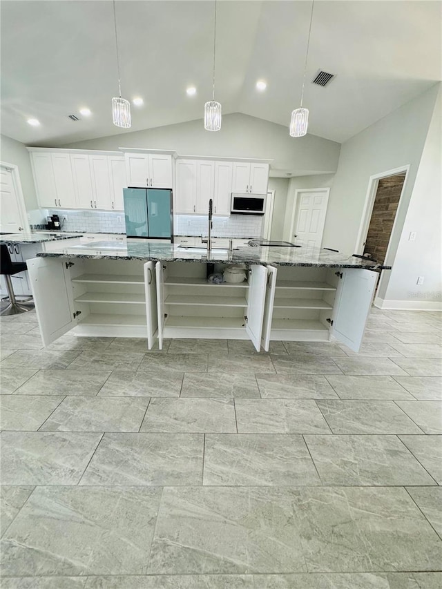 kitchen with lofted ceiling, pendant lighting, a large island, and stone counters