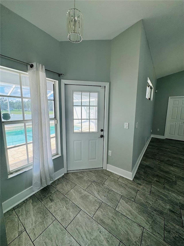 doorway to outside featuring vaulted ceiling, a healthy amount of sunlight, and an inviting chandelier